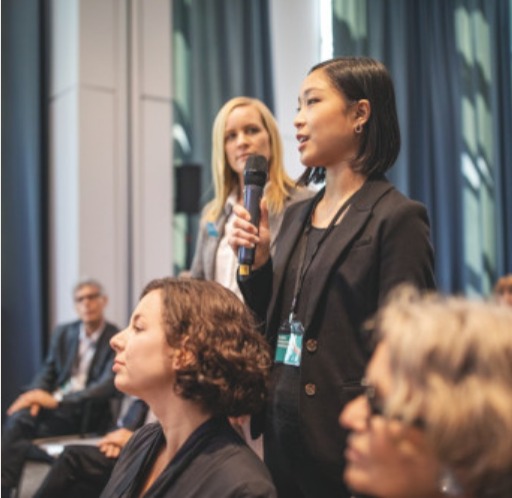 Lady speaking to audience via microphone.