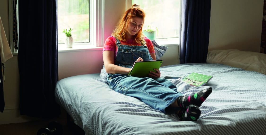 Woman sat on bed using tablet