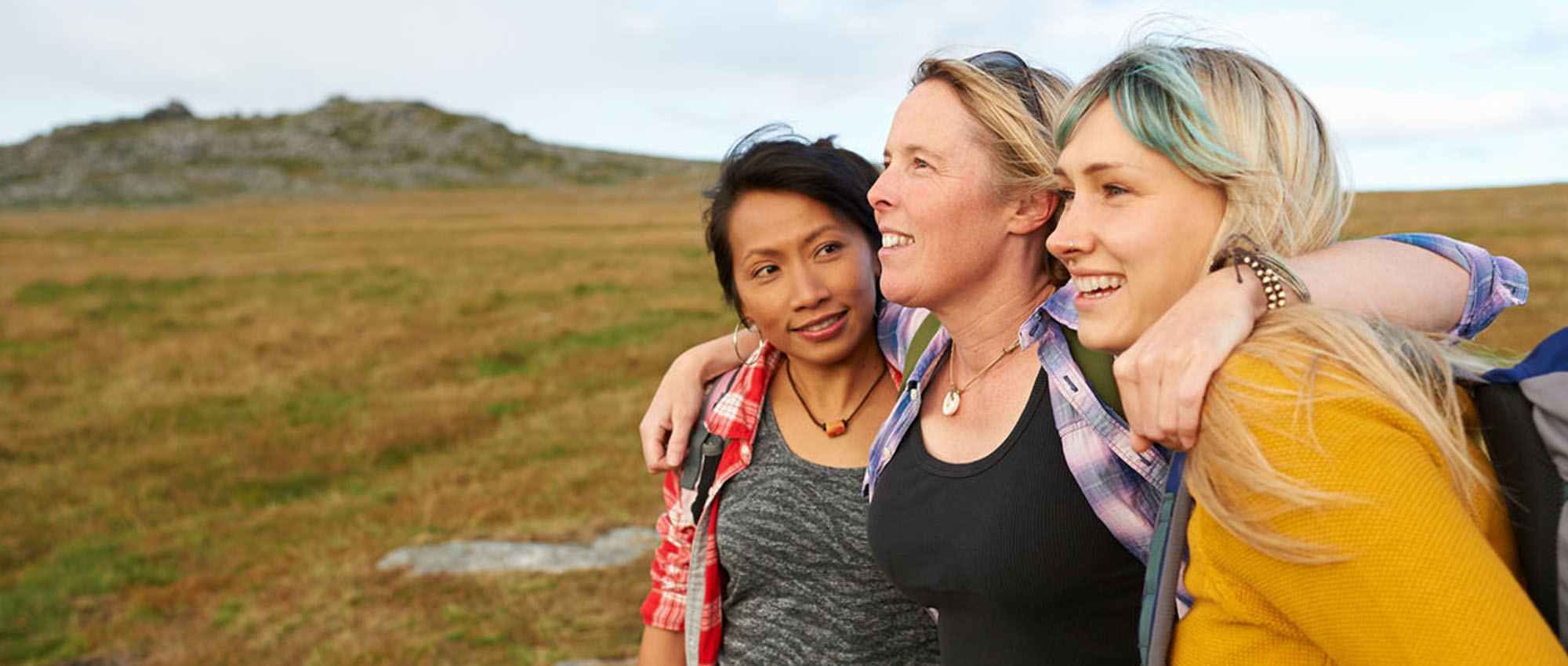 Three happy friends standing in a field