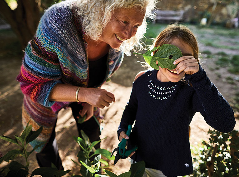 Grandma and child in garden looking at leaf
