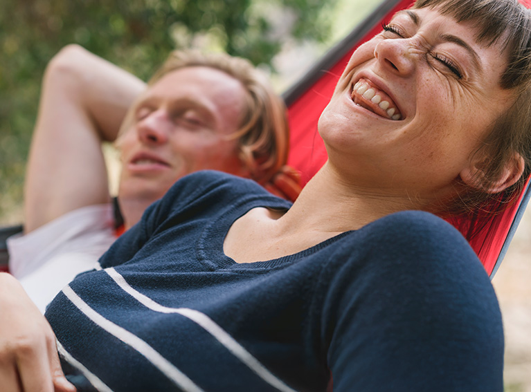 Woman and man lying in hammock laughing