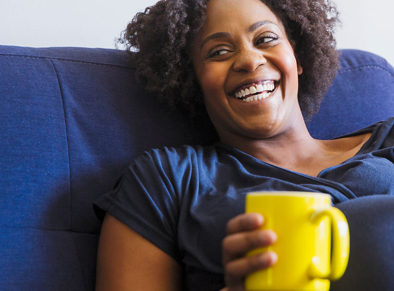 Pregnant woman holding mug and smiling