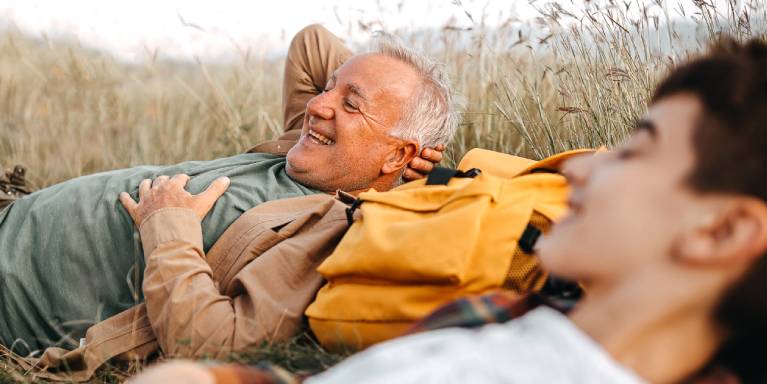 Older man and younger man lying in the grass smiling