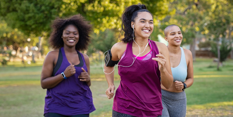 Three ladies jogging and smiling.
