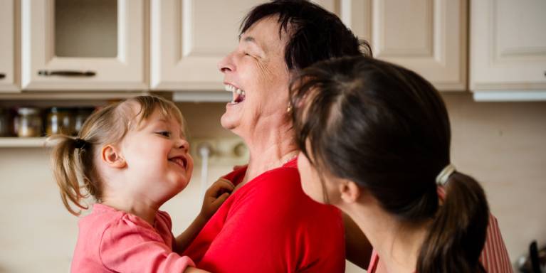 Grandma holding toddler laughing with Mum behind