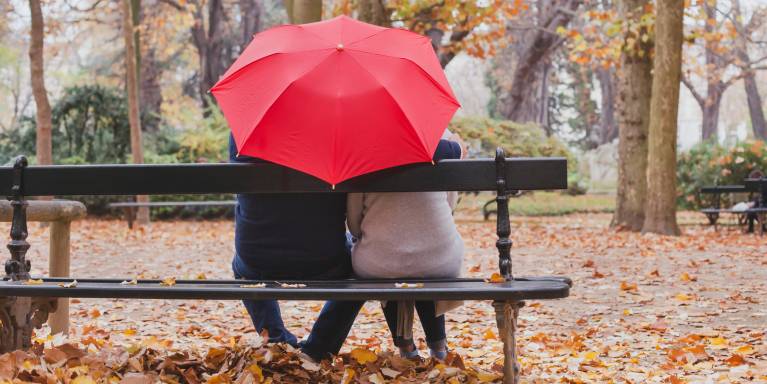 Couple sat on a bench under an umbrella