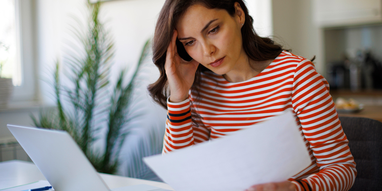 Woman in a red and white stripe top reading a sheet of paper
